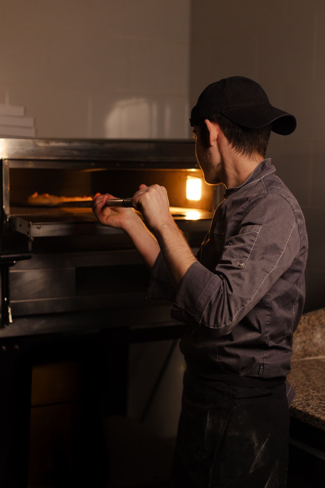 Pizzero sacando una pizza del horno